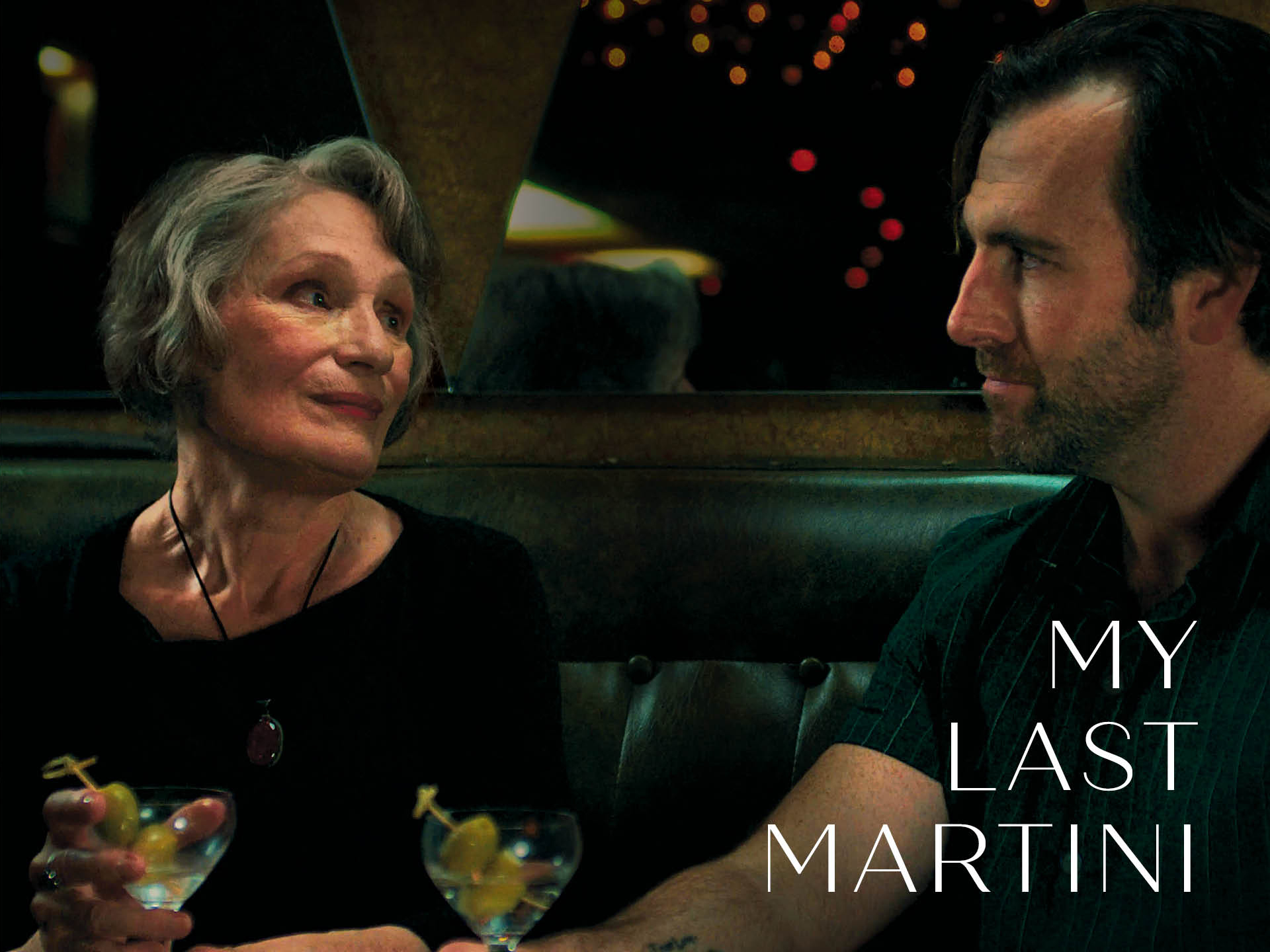 A scene from a film featuring an older woman and a man at a bar, both looking at each other while holding martini glasses. The title "MY LAST MARTINI" is displayed prominently.